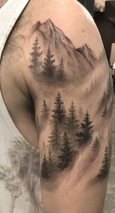 a man with a mountain and trees tattoo on his arm