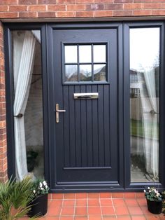 a black front door with two potted plants on the side and one window open