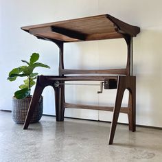 a wooden desk sitting next to a potted plant