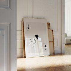 a white frame sitting on top of a hard wood floor next to a wall with black hearts