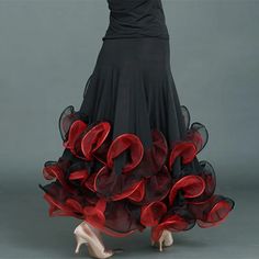 a woman in a black dress with red ruffles on the bottom and side