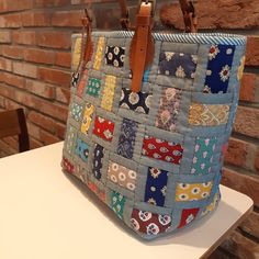 a multicolored patchwork purse sitting on top of a table next to a brick wall