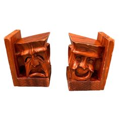 two wooden carved bookends with faces on each one and an opening to the other