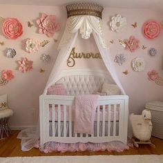 a baby's room decorated in pink and gold with flowers on the wall, crib