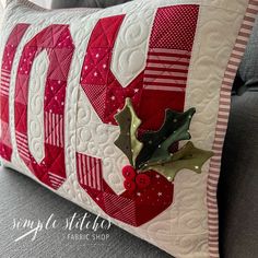 a close up of a pillow on a couch with a holly and mist decoration attached to it