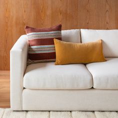 a couch with two pillows on top of it in front of a wood paneled wall