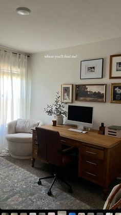 a computer desk sitting in the middle of a living room with pictures on the wall