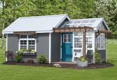 a small gray shed with a blue door and window on the side, surrounded by green grass