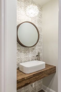 a bathroom sink sitting under a mirror on top of a wooden counter next to a doorway