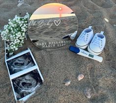 a pair of tennis shoes sitting in the sand next to a memorial plaque and flowers