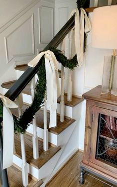 a set of stairs decorated with christmas wreaths and ribbon for the bannister