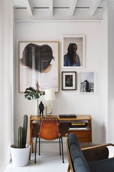 a living room with pictures on the wall and a chair in front of a desk