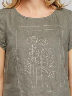 a woman wearing a gray shirt with white flowers on it