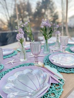 the table is set with purple and white dishes