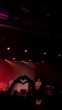 two people making a heart shape with their hands on stage in front of an audience