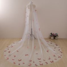 a white bed with pink butterflies on it and a sheer curtain hanging from the ceiling