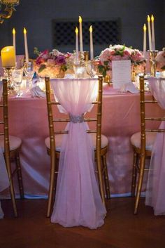 the table is set up with pink linens and gold chairs for an elegant dinner