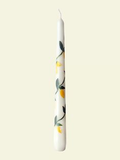 a white candle with yellow flowers on it