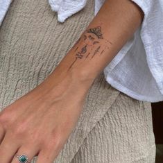 a woman's wrist with a small tattoo on the left side of her arm