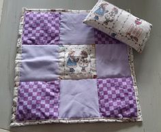 a purple and white patchwork quilt on the floor next to a pillow with two pillows