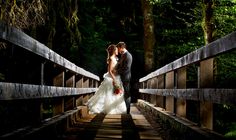 a bride and groom standing on a bridge