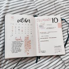 an open planner book on top of a striped bed sheet with the words october written in it