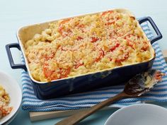 a blue casserole dish filled with macaroni and cheese next to two white plates