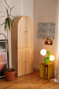 a wooden cabinet sitting next to a potted plant on top of a hard wood floor