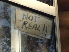 a sign that says not real hanging on the side of a window