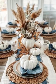 a table set with white pumpkins and blue place settings for thanksgiving or fall dinner