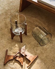 three pieces of wood sit on the floor next to a glass vase and bookcase