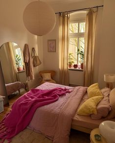 a bed room with a neatly made bed next to a window and a large mirror