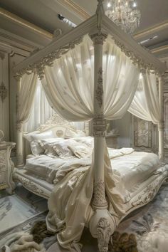 a white canopy bed sitting in a bedroom next to a chandelier and pillows