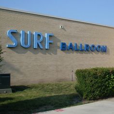 the surf ballroom sign is on the side of the building that has bushes in front of it