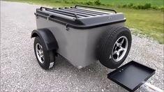 a large gray cooler sitting on the side of a road next to a black box