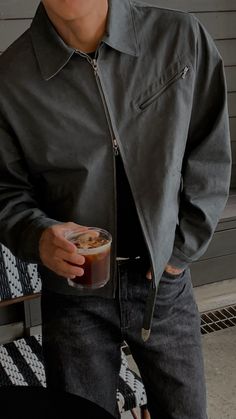 a man holding a drink in his right hand and wearing a black leather jacket on the other