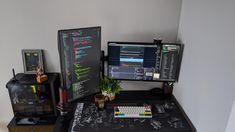 a desk with two computer monitors and a keyboard on it, next to a plant