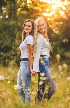 two beautiful young women standing together in the grass