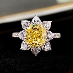 a yellow diamond ring sitting on top of a black surface