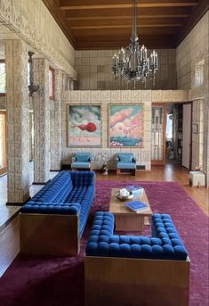 a living room filled with furniture and a chandelier hanging from the ceiling above