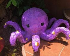 a purple stuffed octopus sitting on top of a tiled floor