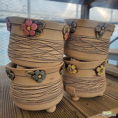 three flower pots sitting on top of a wooden table next to each other with flowers painted on them