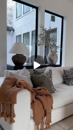 a living room filled with furniture and large windows next to a white couch in front of a window