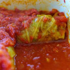 a close up of food in a bowl with sauce on the bottom and an eggplant stuffed inside