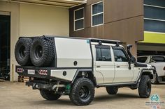 an off road vehicle parked in front of a building with two large tires on it's flatbed