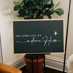 a sign that says oh come let us adore him on it next to a potted plant