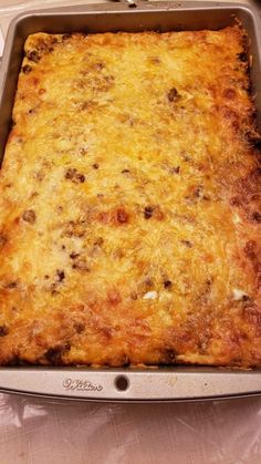 a square casserole dish with cheese and meat in it sitting on a table