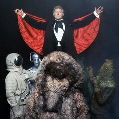 a man in a tuxedo standing on top of a pile of stuffed animals