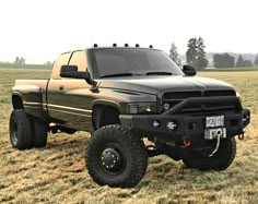 a large black truck parked on top of a grass covered field