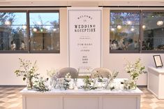 the table is set up for a wedding reception with white flowers and greenery on it